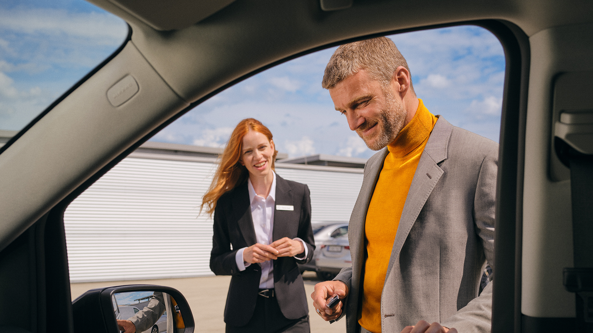 Asiakas ja asiakaspalvelija Mercedes-Benz-auton ulkopuolella autoliikkeen pihalla.